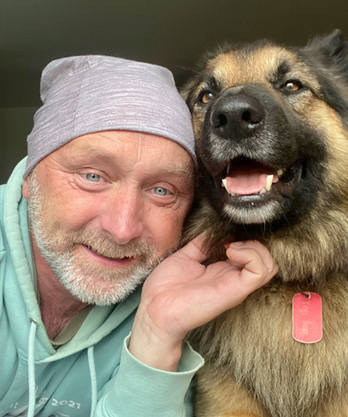 A picture of dance professional Brian Fleming looking into the camera with his dog beside him