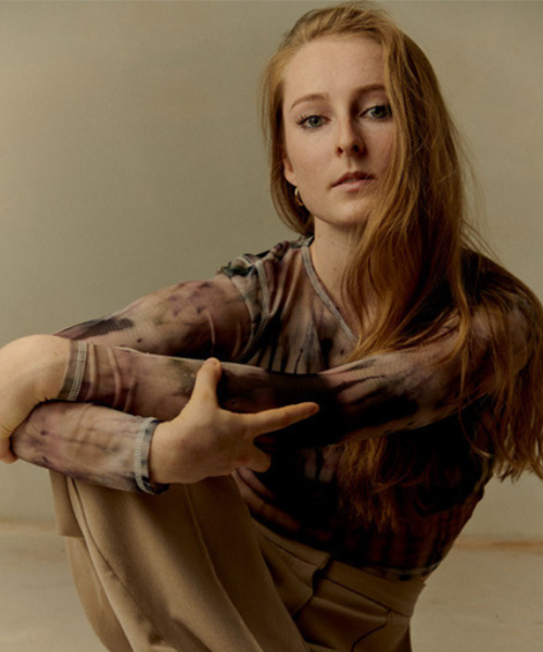 A picture of dance artist Kelly Keesing,sitting on the floor hugging her knees