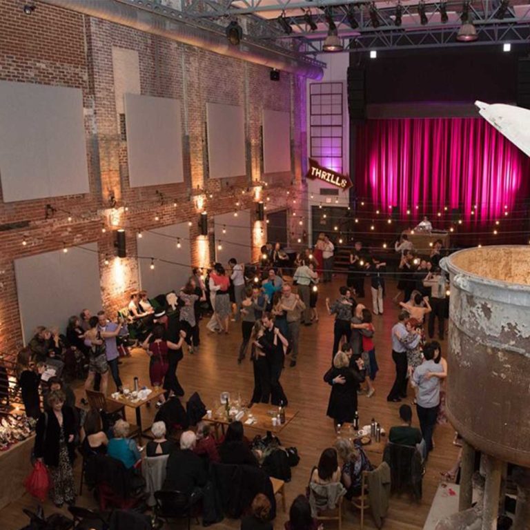 An image of about 30 couples dancing the tango in a ball room setting.